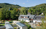 View of Camping Val d'Or in Wiltz, Luxembourg, with mobile homes, playground, and green hills in the background.