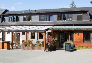 Outdoor view of Camping Val d'Or's main building with a terrace and seating area in Wiltz, Luxembourg.