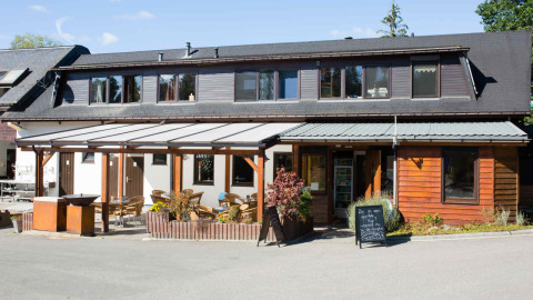 Outdoor view of Camping Val d'Or's main building with a terrace and seating area in Wiltz, Luxembourg.
