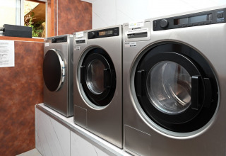 Sala lavanderia con lavatrici industriali al Camping Val d'Or, villaggio vacanze a Wiltz, Lussemburgo.