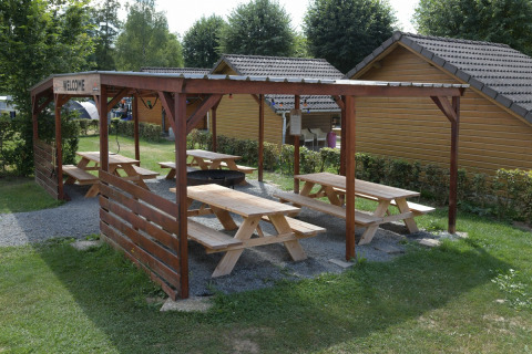 Área de picnic cubierta con mesas de madera en Camping Val d'Or, parque vacacional en Wiltz, Luxemburgo.