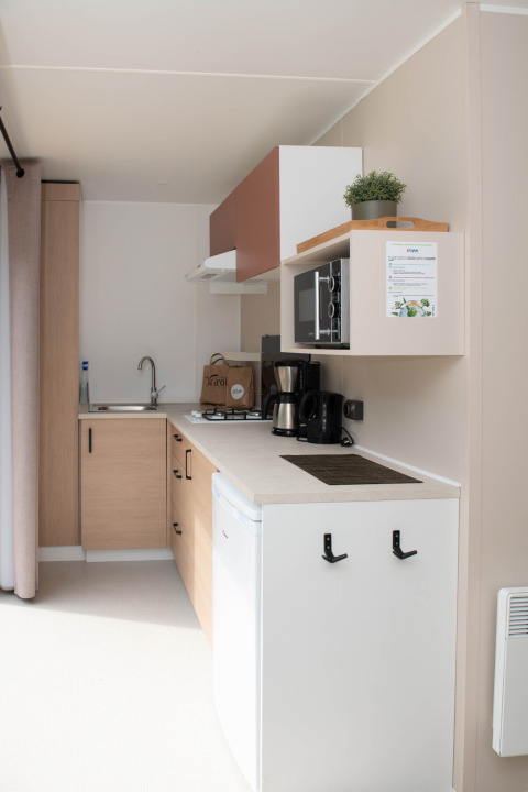 Compact modern kitchen with appliances and coffee maker in a lodge at Camping Val d'Or, Luxembourg.