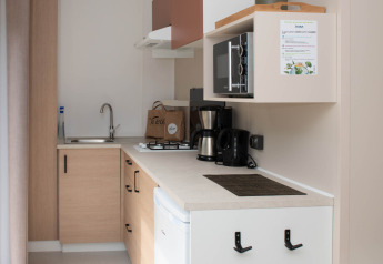 Cucina moderna compatta con elettrodomestici e macchina da caffè in un lodge al Camping Val d'Or, Lussemburgo.