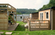 Tiny house lodge at Camping Val d'Or in Luxembourg with wooden decks, outdoor seating, and scenic views.