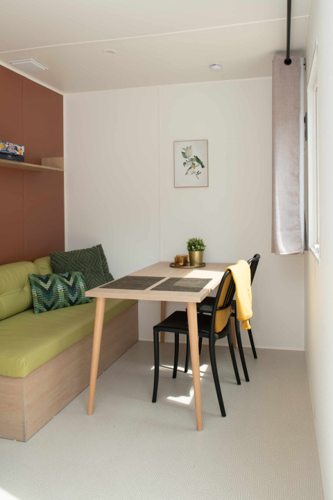 Petit coin repas dans une Tiny house à Camping Val d'Or, Luxembourg, avec table et chaises modernes.