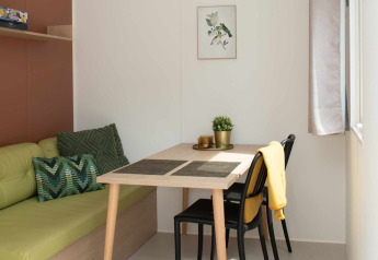 Petit coin repas dans une Tiny house à Camping Val d'Or, Luxembourg, avec table et chaises modernes.