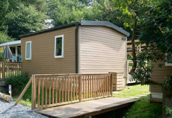 Tiny house lodge au Camping Val d'Or au Luxembourg, entourée d'arbres et dotée d'une terrasse en bois.