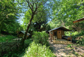 Udsigt over Boslodge um Bierg på Camping Val d'Or i Luxembourg, omgivet af frodige grønne træer.