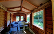 Interior de la Boslodge um Bierg en Camping Val d'Or, Luxemburgo, con sofá, mesa y vista al bosque.