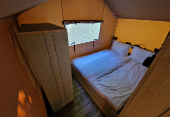 Dormitorio con cama doble y armario en Boslodge um Bierg del Camping Val d'Or, Luxemburgo.