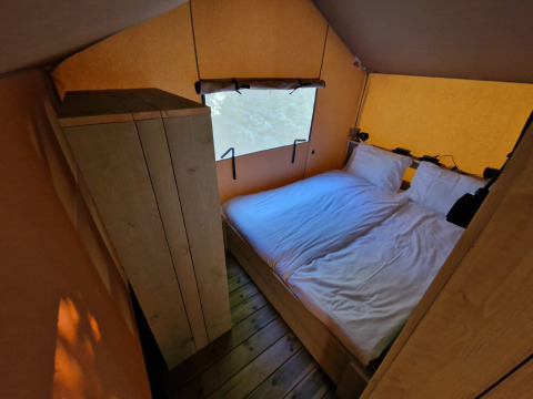 Slaapkamer met tweepersoonsbed en kleerkast in Boslodge um Bierg op Camping Val d'Or, Luxemburg.