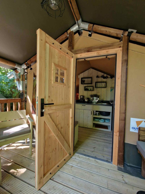 Geöffnete Holztür zu einer gemütlichen Lodge bei Boslodge um Bierg, Camping Val d'Or, Luxemburg.