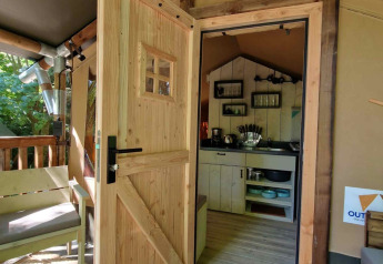 Puerta de madera abierta hacia una acogedora cabaña en Boslodge um Bierg, Camping Val d'Or, Luxemburgo.