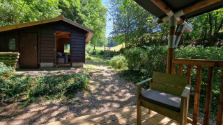 Blick von der Veranda der Boslodge um Bierg, Holzhütte im Wald mit grünem, sonnigem Umfeld.
