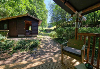 View from the porch at Boslodge um Bierg, showing a wooden cabin and lush green forest scenery.