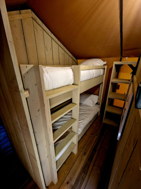 Binnenzicht van een houten stapelbed in Boslodge um Bierg op Camping Val d'Or in Luxemburg.