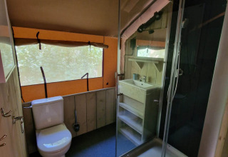 Badkamer in Boslodge um Bierg bij Camping Val d'Or, Luxemburg, met toilet, douche en lavabo.