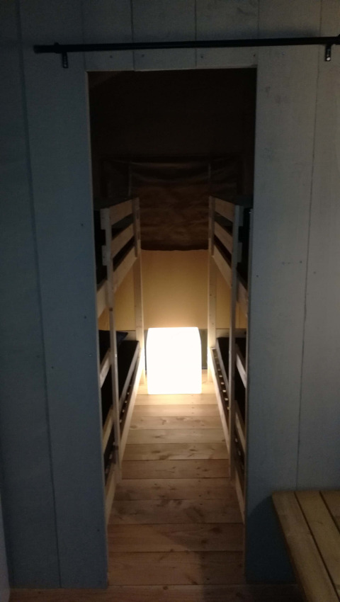 Entrance to Safari tent lodge at Camping Val d'Or in Luxembourg, featuring bunk beds and glowing cube.