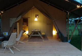 Safaritent bij Camping Val d'Or in Luxemburg, met houten terras, picknicktafel, stoelen en sfeerverlichting.