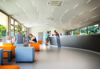 Moderne receptie met kleurrijke zitjes en bezoekers bij hu Norcenni Girasole Village in Toscane, Italië.
