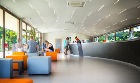 Recepción moderna con asientos coloridos y huéspedes en hu Norcenni Girasole Village en la Toscana, Italia.