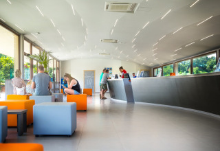 Moderne receptie met kleurrijke zitjes en bezoekers bij hu Norcenni Girasole Village in Toscane, Italië.