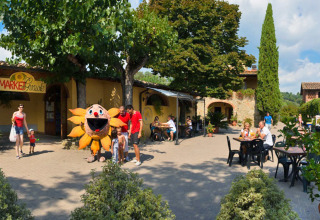 Familias y niños en el hu Norcenni Girasole Village en la Toscana, Italia, junto a una mascota y mesas al aire libre.