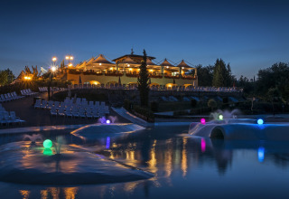 Avondzicht op hu Norcenni Girasole Village vakantiepark in Toscane met verlichte zwembaden en gebouwen.