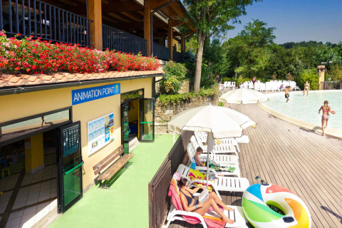 Ligstoelen, parasols en zwembad aan hu Norcenni Girasole Village vakantiepark in Toscane, Italië.