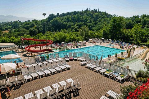 Buitenzwembad en zonneterras met ligstoelen in hu Norcenni Girasole Village vakantiepark, Toscane, Italië.