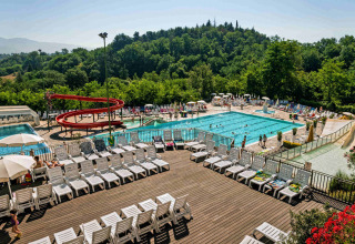 Buitenzwembad en zonneterras met ligstoelen in hu Norcenni Girasole Village vakantiepark, Toscane, Italië.