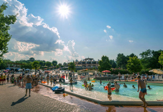 Villaggio turistico in Toscana con famiglie che si divertono in piscina sotto il sole estivo luminoso.