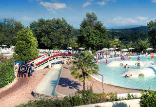 Famiglie si divertono tra giochi d'acqua e relax in piscina al hu Norcenni Girasole Village in Toscana.