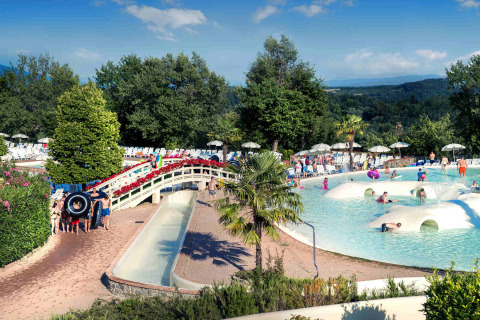 Famiglie si divertono tra giochi d'acqua e relax in piscina al hu Norcenni Girasole Village in Toscana.