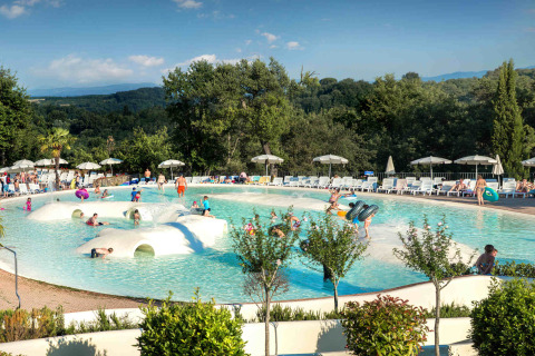 Niños y familias disfrutan de una piscina poco profunda en hu Norcenni Girasole Village en la Toscana, Italia.