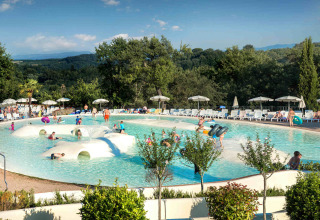 Famiglie e bambini si divertono nella piscina con giochi d'acqua al hu Norcenni Girasole Village in Toscana.