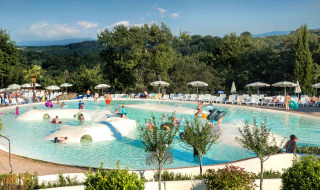 Niños y familias disfrutan de una piscina poco profunda en hu Norcenni Girasole Village en la Toscana, Italia.