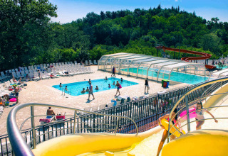 Zona piscina all’aperto con scivolo d’acqua e lettini al hu Norcenni Girasole Village in Toscana, Italia.