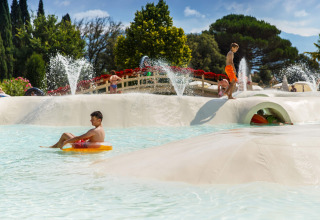 Kinderen spelen in een waterpark met glijbanen en fonteinen bij hu Norcenni Girasole Village, Toscane, Italië.