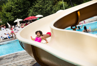 Bambino in costume rosa scivola su uno scivolo d’acqua al Norcenni Girasole Village in Toscana, Italia.