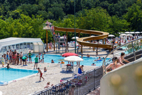 Persone che si divertono in piscina e sullo scivolo al villaggio hu Norcenni Girasole in Toscana, Italia.
