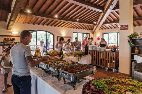 Comida buffet en hu Norcenni Girasole Village, un parque vacacional en la Toscana, Italia, con personas sirviéndose.