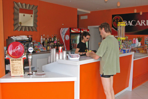 Hombre en bañador pidiendo bebidas en el bar de hu Norcenni Girasole Village, Toscana, Italia.