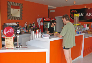 Man in swim trunks ordering drinks at the bar in hu Norcenni Girasole Village, Tuscany, Italy.