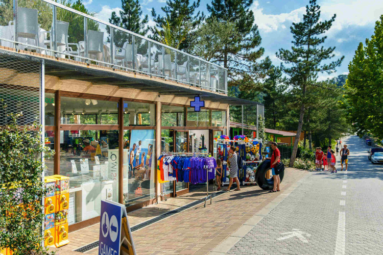 Winkel en bezoekers bij hu Norcenni Girasole Village, een vakantiepark omringd door bomen in Toscane.