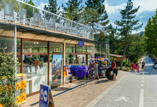 Tienda y visitantes en hu Norcenni Girasole Village, un parque vacacional rodeado de árboles en la Toscana.