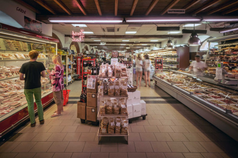 Supermarkt in hu Norcenni Girasole Village, Toscane, Italië, met versafdelingen en klanten die winkelen.
