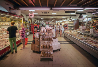 Supermarkt in hu Norcenni Girasole Village, Toscane, Italië, met versafdelingen en klanten die winkelen.