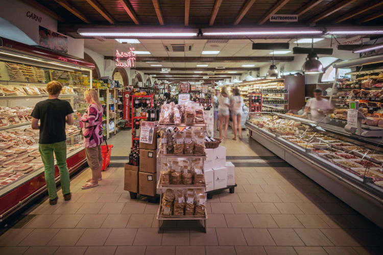 Supermarkt in hu Norcenni Girasole Village, Toscane, Italië, met delicatessenafdeling en winkelend publiek.