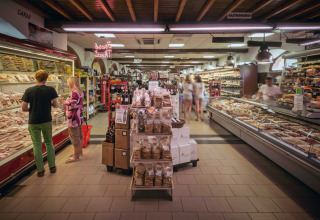 Supermarket inside hu Norcenni Girasole Village, Tuscany, Italy, featuring deli counters and shoppers.